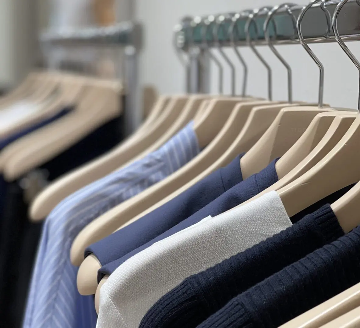 A rack of clothes with wooden clothes hangers